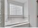 Elegant bathroom with soaking tub, glass block window, and white tile surround at 6610 Royal Oakland Dr, Indianapolis, IN 46236