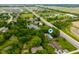 Aerial view of the home, surrounding greenery, pond, and roadway at 7482 W Us Highway 40, Indianapolis, IN 46229