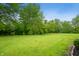 Expansive backyard with lush green grass, mature trees, and garden beds, perfect for outdoor activities and relaxation at 7482 W Us Highway 40, Indianapolis, IN 46229