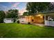 Well-maintained backyard with stone exterior, covered patio, lush green lawn, and mature trees at 7482 W Us Highway 40, Indianapolis, IN 46229