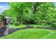 A tranquil backyard with a stone pathway, mulched flowerbeds, lush greenery and sunroom entrance at 8641 Cholla Rd, Indianapolis, IN 46240