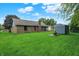 Expansive backyard showcasing a well-kept lawn, brick house, storage shed, and inviting fire pit at 926 Brookside Ln, Plainfield, IN 46168