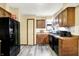 Galley kitchen features dark appliances, wood cabinets and light colored vinyl flooring at 926 Brookside Ln, Plainfield, IN 46168