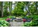 Relaxing backyard firepit area with Adirondack chairs, mature trees, and beautiful garden surroundings at 9550 Copley Dr, Indianapolis, IN 46260