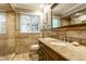Well-lit bathroom with travertine countertops, a mirror, and a toilet near the corner shower at 9550 Copley Dr, Indianapolis, IN 46260