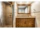 Bathroom showcasing a wood vanity, framed mirror and stone tiled shower with glass door at 9550 Copley Dr, Indianapolis, IN 46260