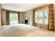 Open living room with a fireplace, sliding glass door, and large windows at 9550 Copley Dr, Indianapolis, IN 46260