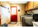 Modern laundry room featuring a new washer and dryer, cabinets and a bright red back door at 1010 Lakewood N Dr, Brownsburg, IN 46112