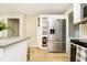 Bright kitchen featuring stainless steel fridge, light wood floors, and white cabinets with built-in storage at 10245 Briar Creek Ln, Carmel, IN 46033