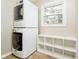 Functional laundry room with stacked washer and dryer, a small window, and cubby shelving for storage at 10245 Briar Creek Ln, Carmel, IN 46033