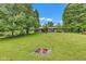 Backyard featuring a large manicured lawn, a fire pit, and a well-maintained home exterior at 10444 N State Road 9, Fountaintown, IN 46130