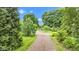 Gravel driveway amidst lush trees and greenery leads to this home at 10444 N State Road 9, Fountaintown, IN 46130