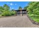 Two-story home with stone exterior, two-car garage, balcony, and gravel driveway amid green trees at 10444 N State Road 9, Fountaintown, IN 46130