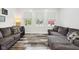 Bright living room with three windows providing natural light, complemented by modern, comfortable gray couches at 117 N Market St, Thorntown, IN 46071