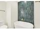 Elegant bathroom features a modern standalone tub, toilet, and vertically stacked green tile at 16598 Dominion Dr, Fortville, IN 46040