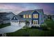 Inviting two-story home featuring a well-kept lawn and a spacious two-car garage at twilight at 16598 Dominion Dr, Fortville, IN 46040
