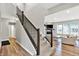 Open concept living room with hardwood floors and a cozy fireplace, adjacent to a stairway at 16598 Dominion Dr, Fortville, IN 46040