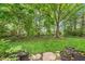 Lush backyard with mature trees, garden beds and a stone paver patio at 19061 Fairfield Blvd, Noblesville, IN 46060