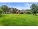 Large backyard featuring a brick house, a lush lawn, and mature trees at 2027 Round Barn Ct, Anderson, IN 46017