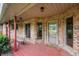 Charming covered front porch with a wooden bench and red brick exterior at 2027 Round Barn Ct, Anderson, IN 46017