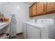 Functional laundry room with washer, dryer, upper cabinets, and an ironing board at 2027 Round Barn Ct, Anderson, IN 46017