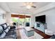 Bright living room with a ceiling fan, large windows leading to a balcony, and a stylish blue entertainment center at 20971 Shoreline Ct # 201, Noblesville, IN 46062