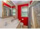 A bathroom with a neutral sink and vanity against a red painted wall, and a shower with a window at 2445 S Bolton Ave, Indianapolis, IN 46203
