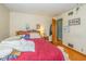 View of a bedroom with hardwood floors, a red bedspread, and a built-in headboard with shelves at 2445 S Bolton Ave, Indianapolis, IN 46203