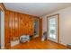 View of a living room area with natural wood walls, wood floors, and an exterior door at 2445 S Bolton Ave, Indianapolis, IN 46203
