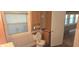 Bright bathroom includes built-in cabinet, window, and standard toilet, tiled walls, and ceramic tile flooring at 3107 N 100 W, Shelbyville, IN 46176
