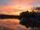 Scenic lake view at sunset with still water reflecting the colorful sky, trees, and nearby houses at 3403 Island Way, Indianapolis, IN 46214