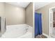 Bright bathroom featuring a white garden tub and blue shower curtain at 3803 Churchman Woods Blvd, Indianapolis, IN 46203