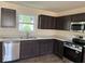 Modern kitchen with stainless steel appliances, dark cabinets, laminate countertops, and a window over the sink at 3805 Windstar Way, Columbus, IN 47203