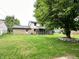 Spacious backyard featuring a large tree and partial view of the brick house with a screened-in porch at 5130 Navajo Ct, Columbus, IN 47203