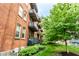 Exterior of the red brick building with balconies, green trees, and landscaped area at 55 S Harding St # 308, Indianapolis, IN 46222