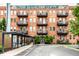 The H. Lauter Lofts, a red brick apartment building, featuring charming balconies and beautiful greenery at 55 S Harding St # 308, Indianapolis, IN 46222