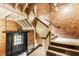 Stairwell featuring brick walls, painted wood trim and carpeted stairs, offering both character and functionality at 55 S Harding St # 308, Indianapolis, IN 46222