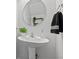 Elegant pedestal sink with a round mirror and modern fixtures creates a charming and functional bathroom space at 5848 Sheffield Ln, Whitestown, IN 46075
