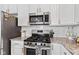 Kitchen boasts stainless steel appliances, including a modern gas stove, microwave, and white cabinets at 5848 Sheffield Ln, Whitestown, IN 46075