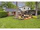 Well-maintained backyard showcasing a wooden deck with a hot tub, seating area, and mature trees at 6115 E 65Th Pl, Indianapolis, IN 46220