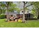 Landscaped backyard featuring a wooden deck with seating, a hot tub, and a screened-in porch at 6115 E 65Th Pl, Indianapolis, IN 46220