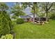 Scenic backyard view with lush green lawn, wooden deck, mature trees, and partial fence at 6115 E 65Th Pl, Indianapolis, IN 46220