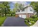 Exterior of home with a two-car garage, paved driveway, brick accents, and lush landscaping at 6115 E 65Th Pl, Indianapolis, IN 46220