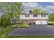 Rear exterior view showcasing a two-car garage, paved driveway, brick facade, and well-maintained landscaping at 6115 E 65Th Pl, Indianapolis, IN 46220