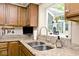 Close-up of a kitchen sink with granite countertops and wooden cabinetry at 6115 E 65Th Pl, Indianapolis, IN 46220