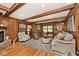 Comfortable living room with wood paneling, fireplace, hardwood floors and access to the outside at 6115 E 65Th Pl, Indianapolis, IN 46220