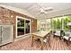 This screened-in porch has a brick floor, a ceiling fan, and rustic wooden furniture set around a table at 6115 E 65Th Pl, Indianapolis, IN 46220