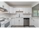 Modern kitchen with white cabinetry, stainless steel appliances, and gray wood-look flooring at 625 E 106Th St, Carmel, IN 46280