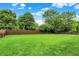 Expansive backyard featuring a lush lawn, mature trees, and privacy fence under a bright blue sky at 7312 Drum Castle Ct, Indianapolis, IN 46259