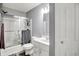 Compact bathroom featuring a shower-tub combo with a glass door, paired with a white vanity at 9001 Harrison Run Ct, Indianapolis, IN 46256